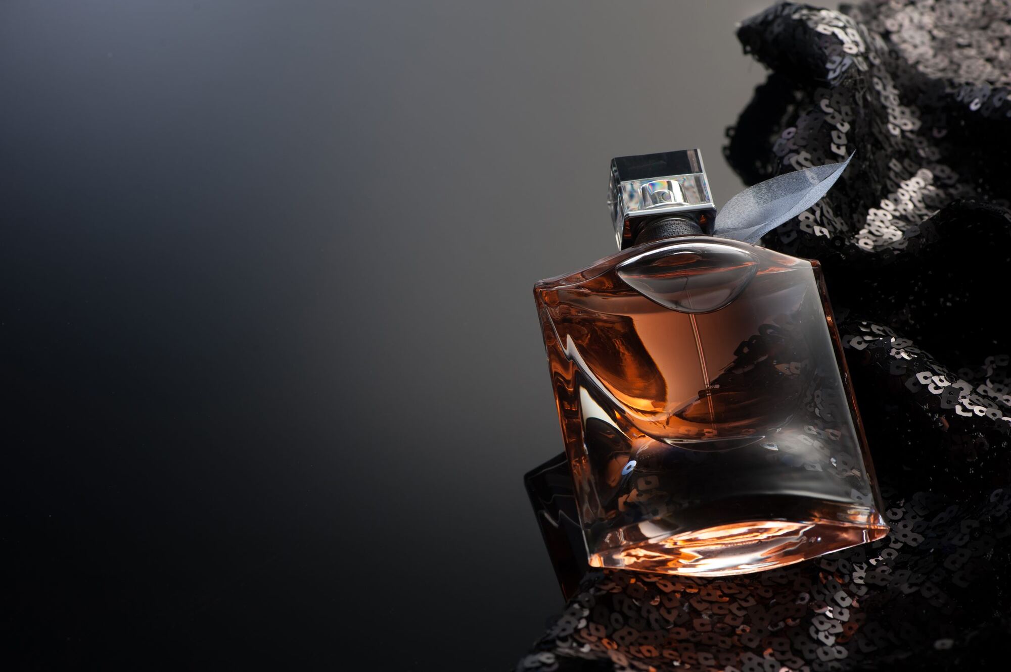 Perfume bottle on dark sequined fabric